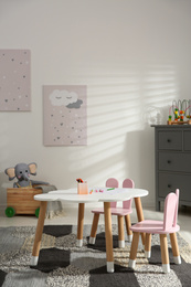 Photo of Little table and chairs with bunny ears in children's room. Interior design