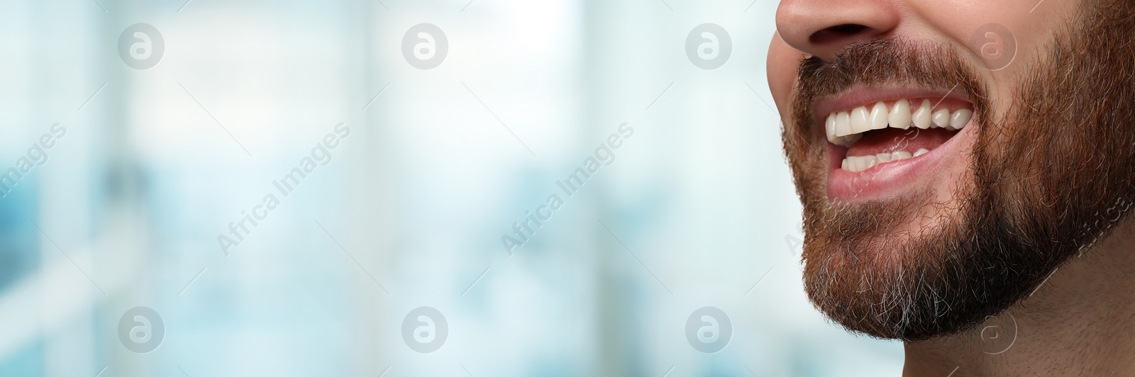 Image of Man with clean teeth smiling on blurred background, closeup. Banner design with space for text