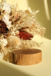 Photo of Presentation of product. Wooden podium and dry flowers on yellow background