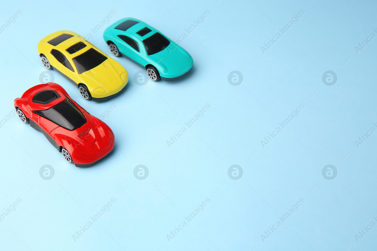 Photo of Different bright cars on light blue background, space for text. Children`s toys