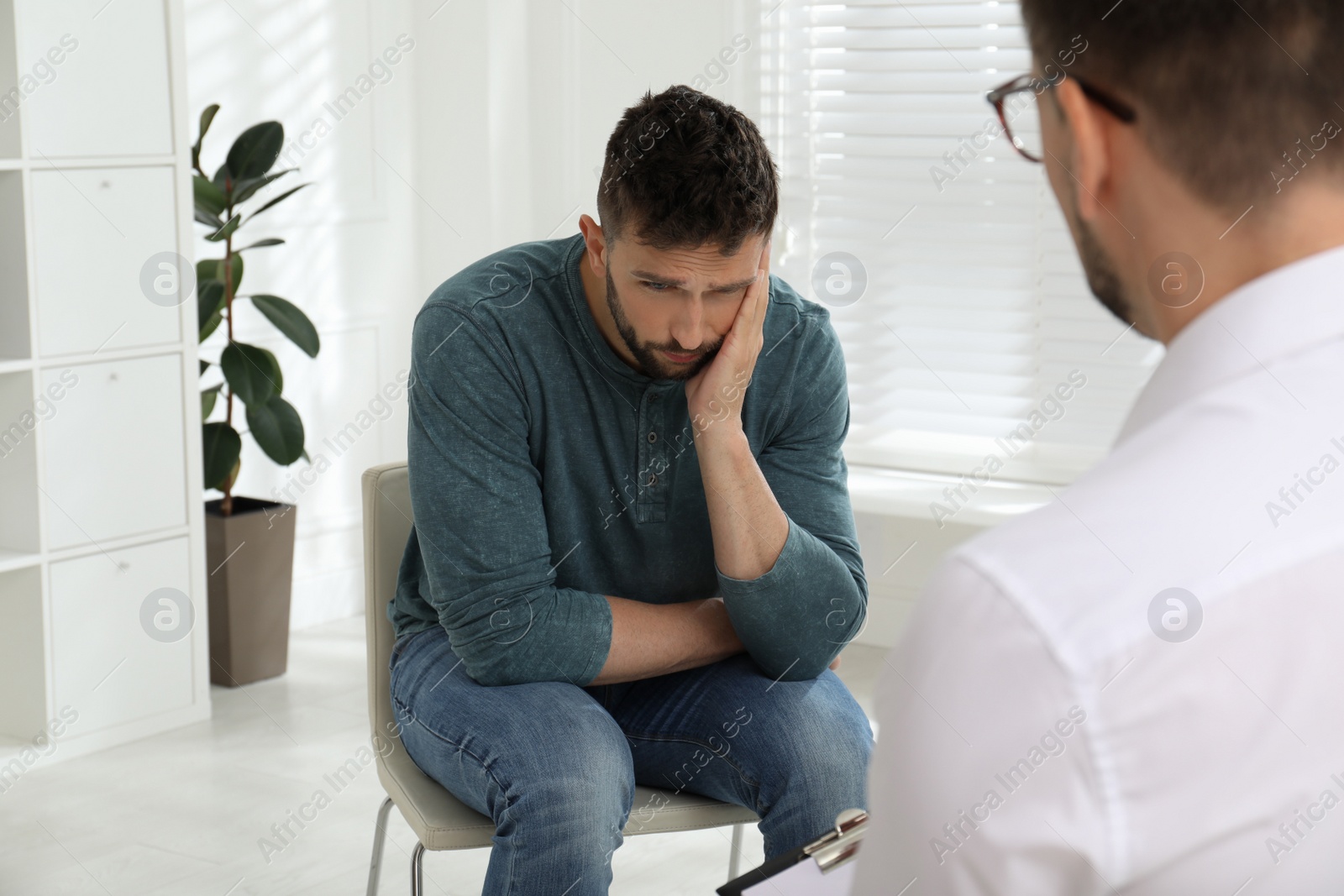 Photo of Psychotherapist working with drug addicted man indoors