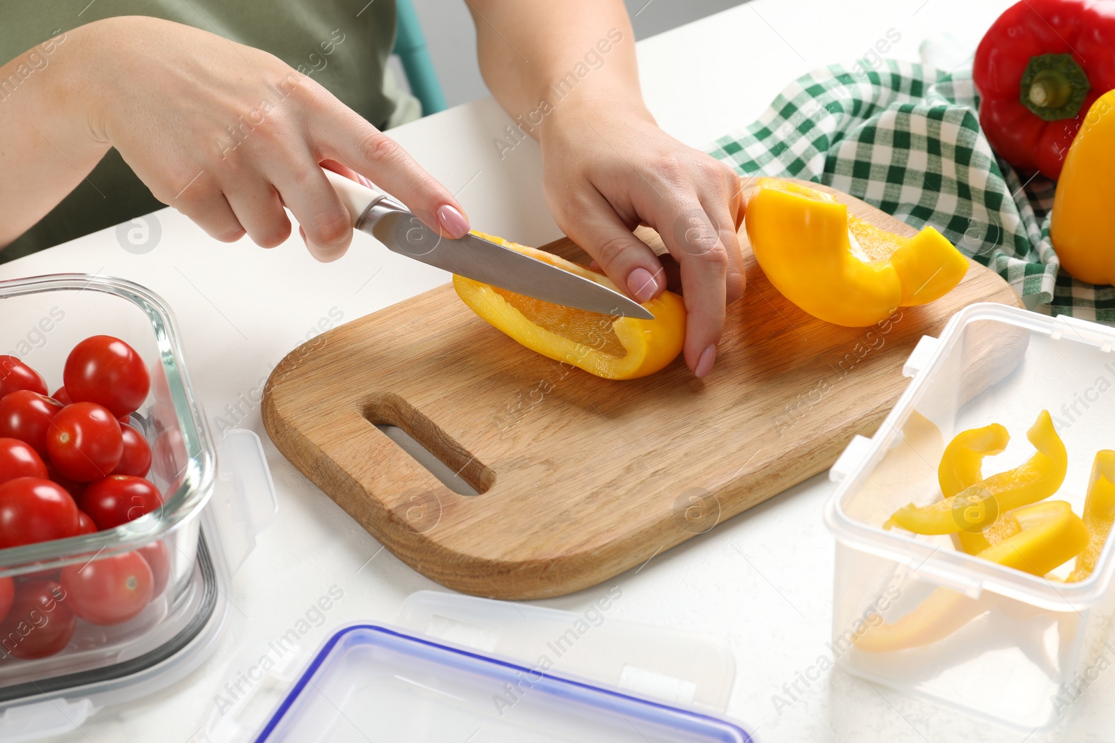 Photo of Woman cutting bell pepper and containers with fresh products on white table, closeup. Food storage