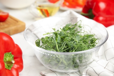 Photo of Fresh microgreen and other ingredients for tasty salad on white table, closeup