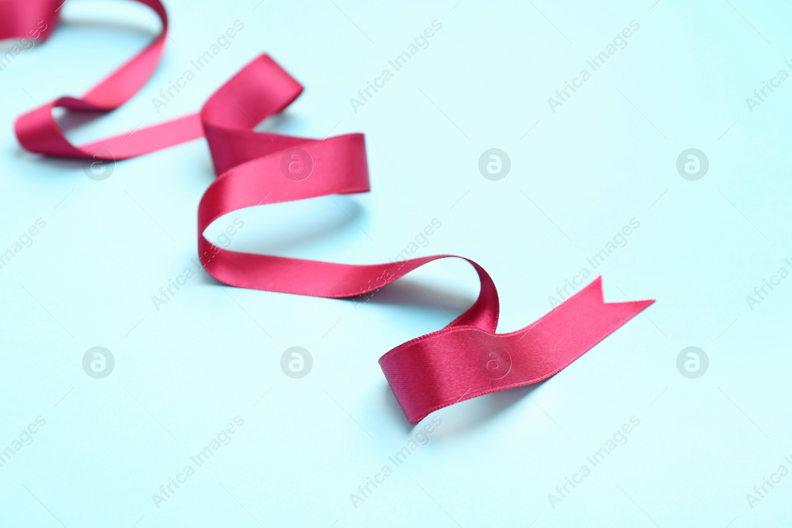 Photo of Simple pink ribbon on color background. Festive decoration