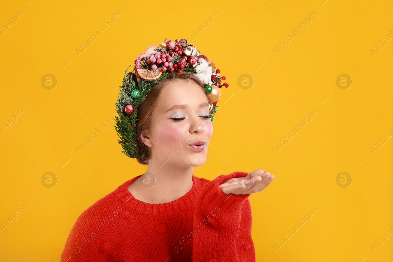 Photo of Beautiful young woman wearing Christmas wreath on yellow background