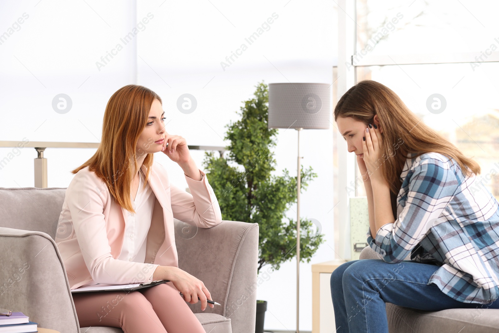 Photo of Young female psychologist working with teenage girl in office