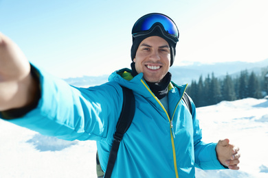 Photo of Happy man taking selfie in mountains. Winter vacation