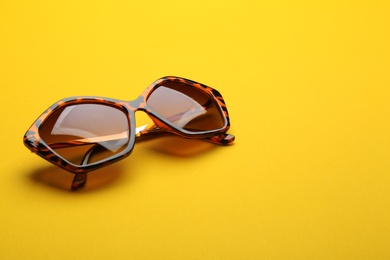 Stylish sunglasses on yellow background. Fashionable accessory