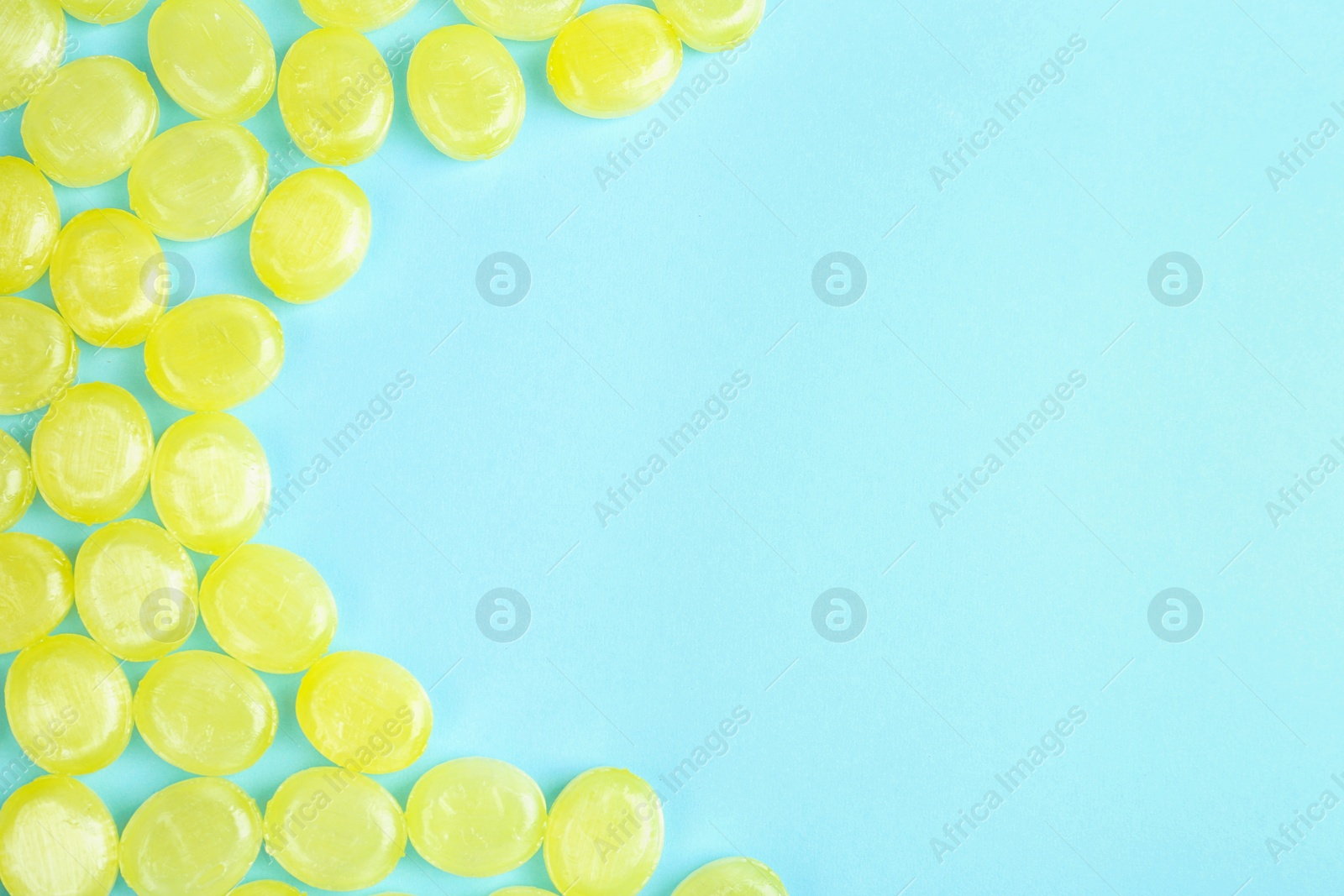 Photo of Many delicious lemon drops on light blue background, flat lay. Space for text