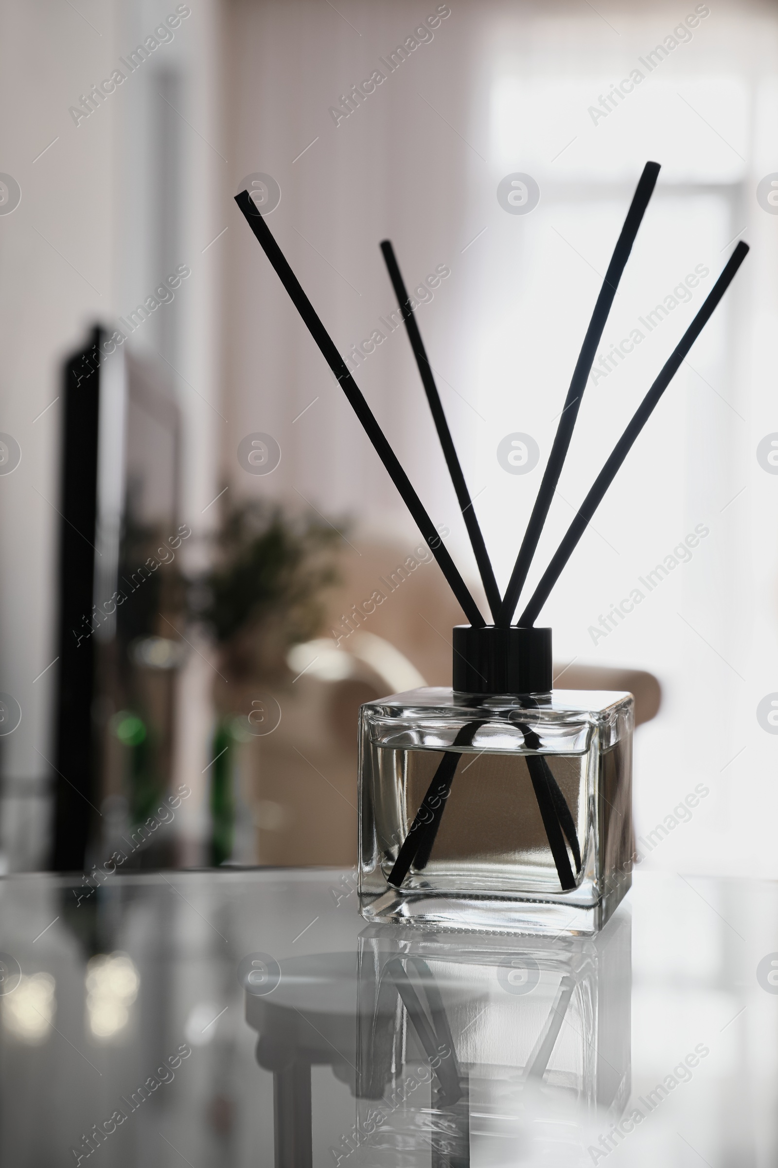 Photo of Aromatic reed air freshener on table indoors, space for text