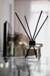 Photo of Aromatic reed air freshener on table indoors, space for text