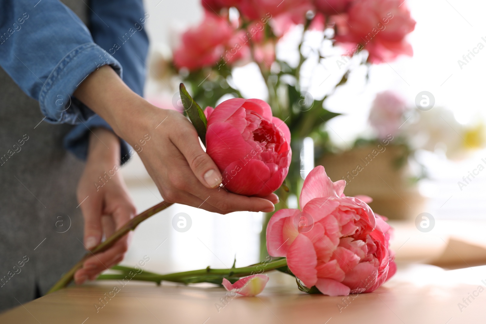 Photo of Florist making beautiful peony bouquet at table, closeup