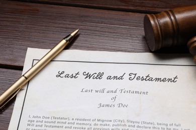 Photo of Last Will and Testament with gavel and pen on wooden table, closeup