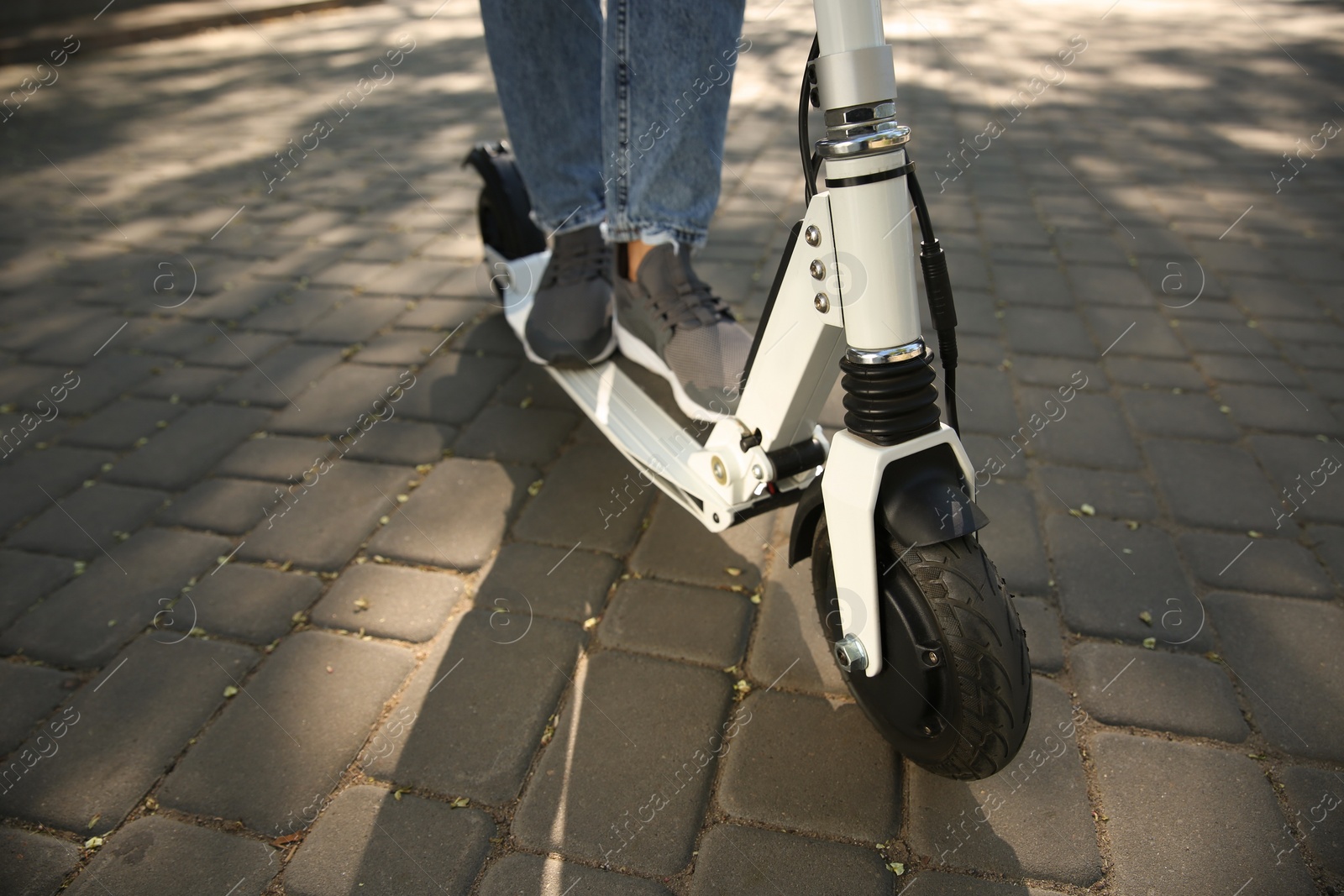 Photo of Woman riding electric kick scooter outdoors, closeup