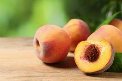 Cut and whole fresh ripe peaches on wooden table against blurred background, closeup. Space for text