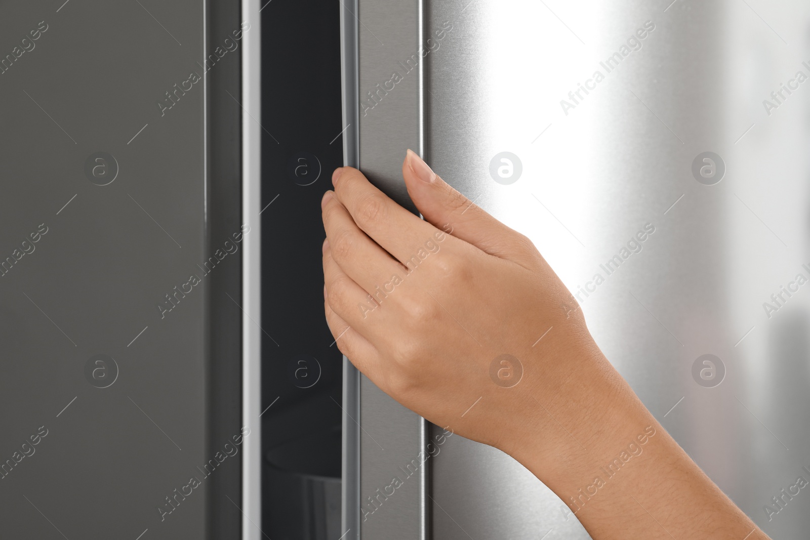 Photo of Woman opening modern refrigerator door, closeup view