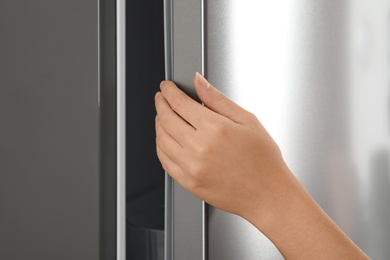 Photo of Woman opening modern refrigerator door, closeup view