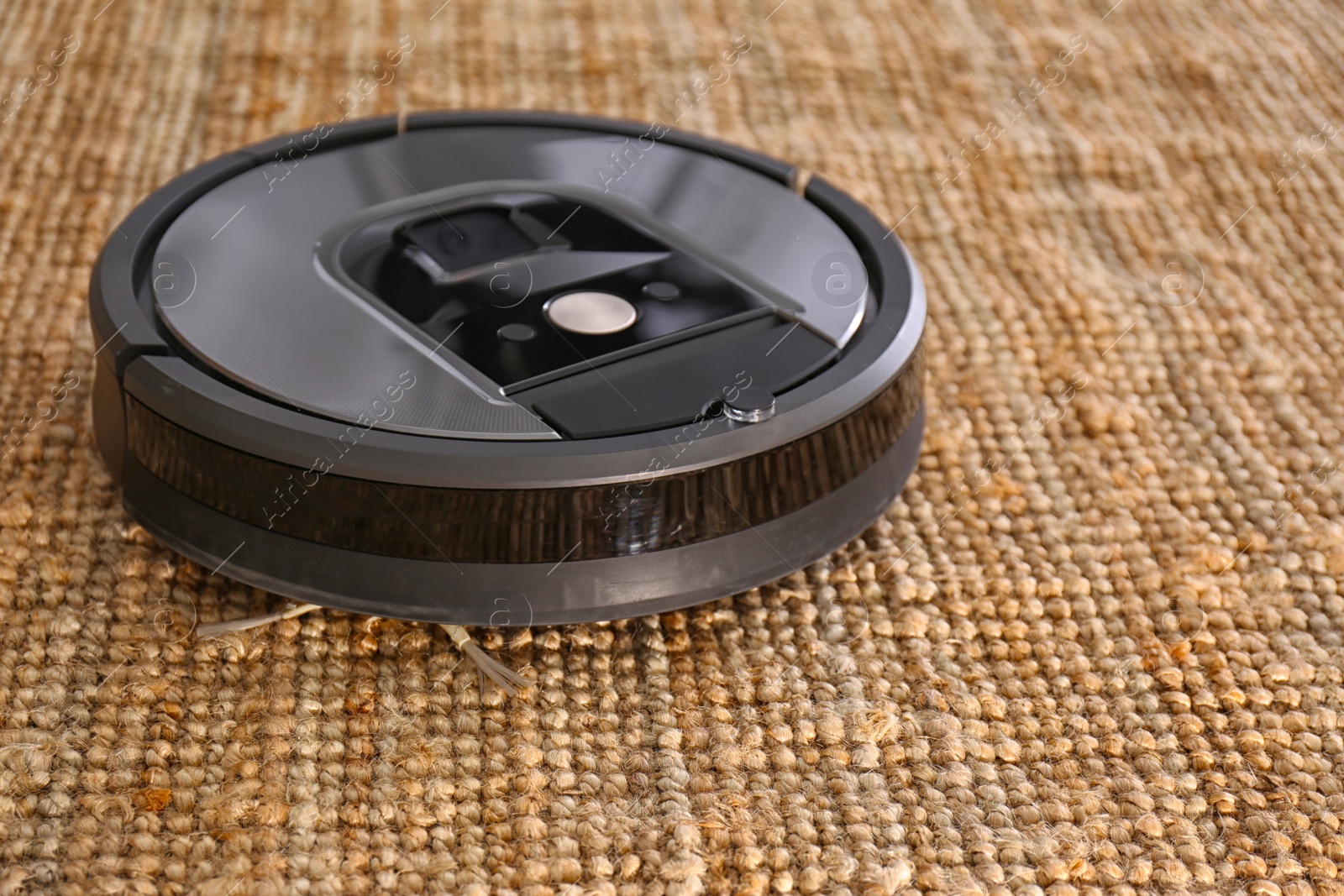Photo of Modern robotic vacuum cleaner on brown rug