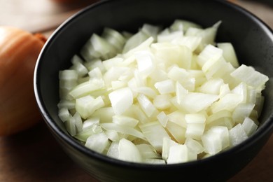 Bowl with cut onion on table, closeup