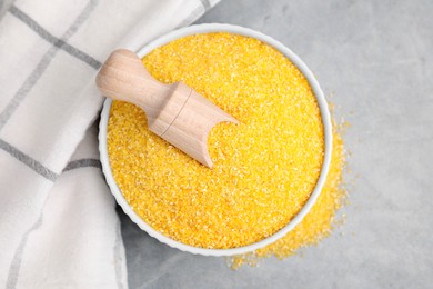 Photo of Raw cornmeal and scoop in bowl on grey table, top view