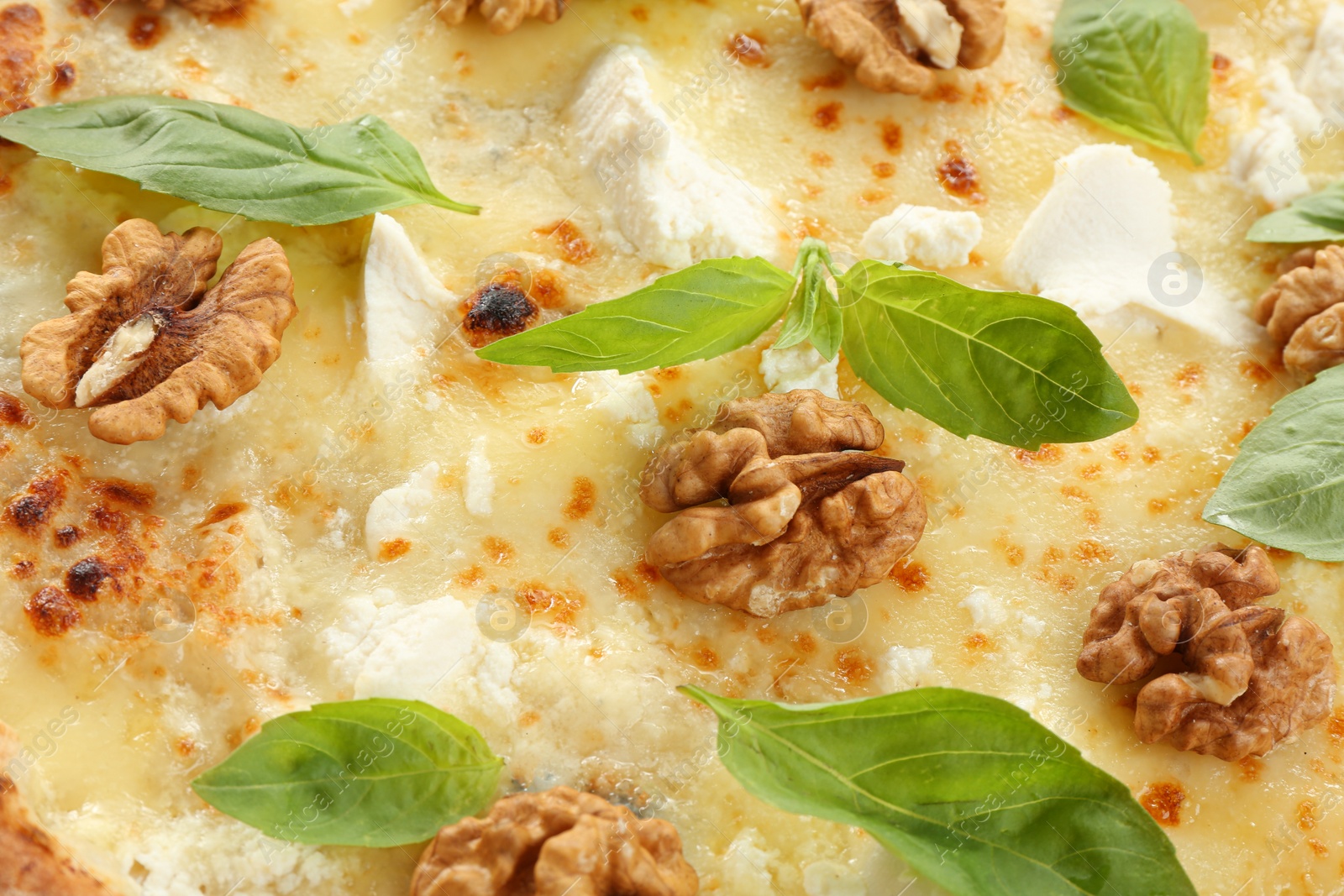 Photo of Delicious cheese pizza with walnuts and basil as background, closeup