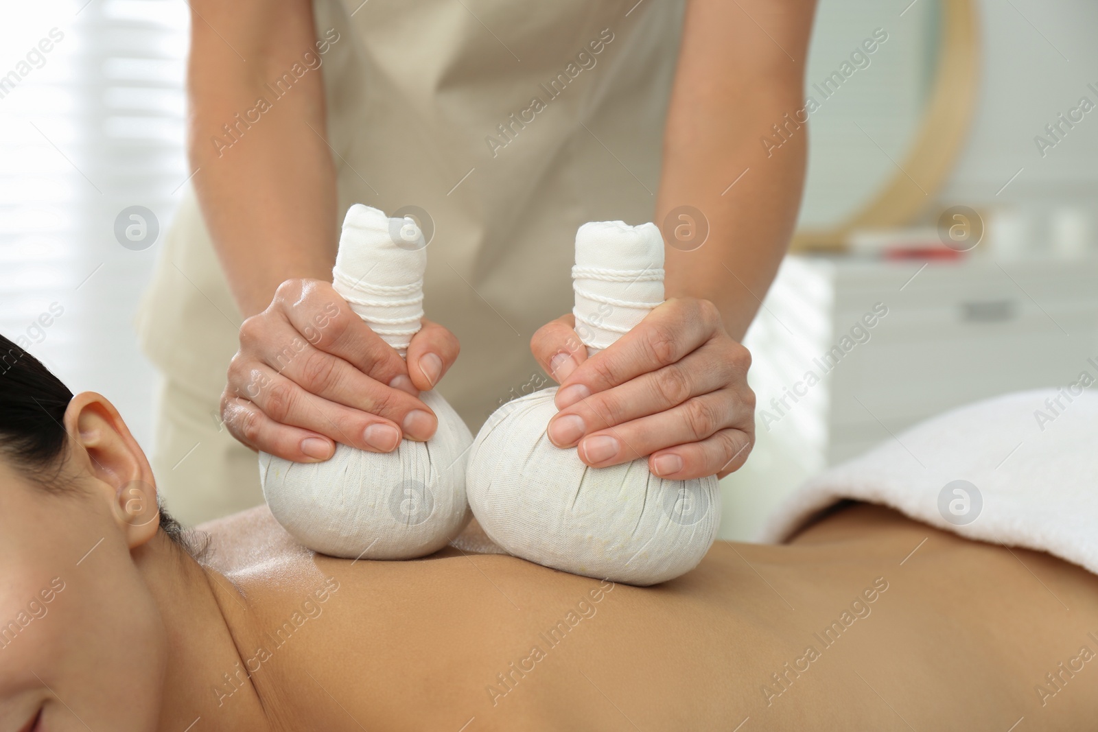 Photo of Young woman receiving herbal bag massage in spa salon, closeup