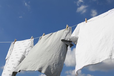 Photo of Washing line with clean clothes against sky. Drying laundry outside