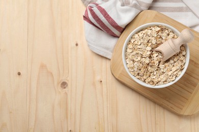 Photo of Bowl and scoop with oatmeal on wooden table, top view. Space for text