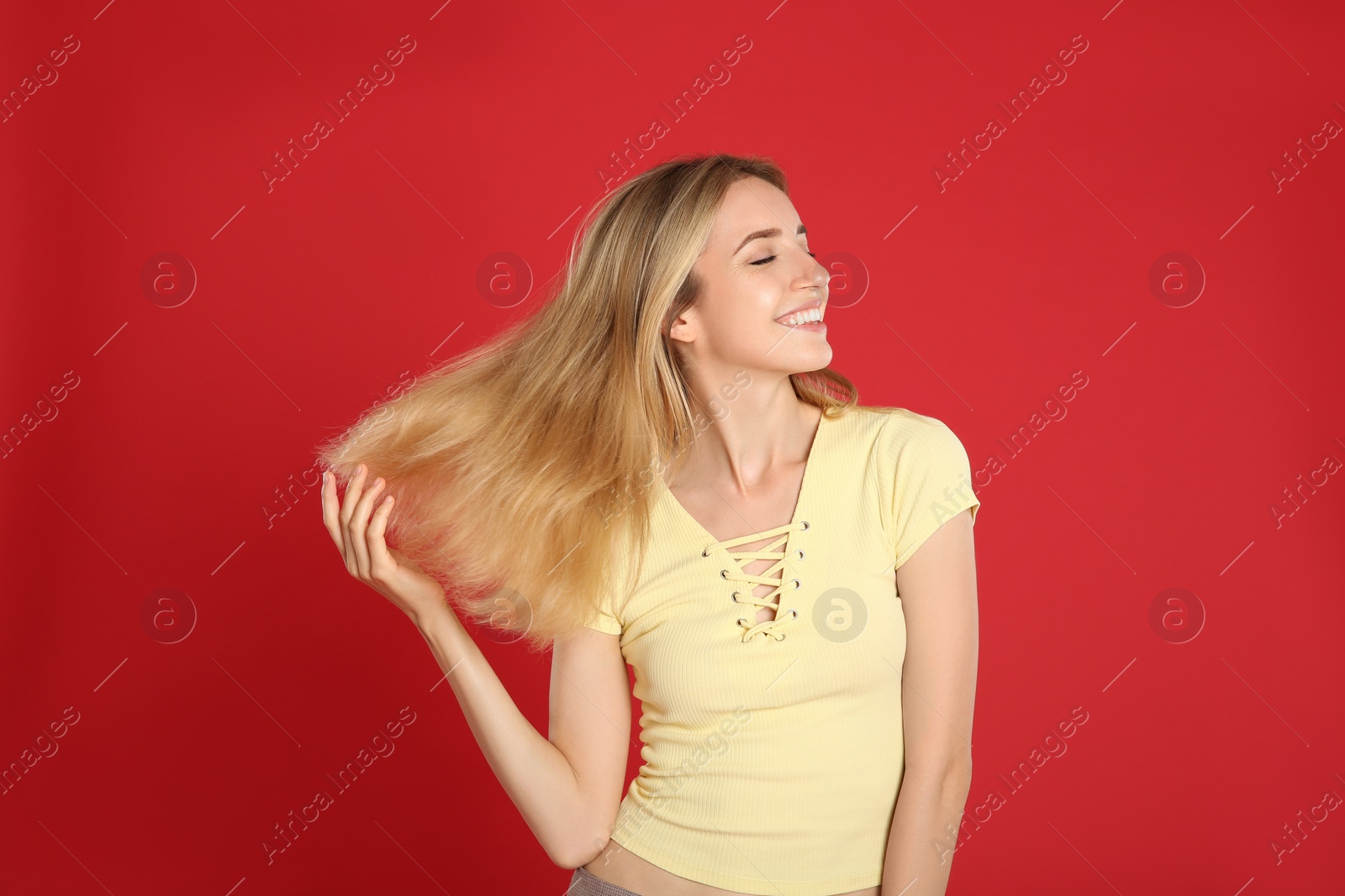 Photo of Portrait of beautiful young woman with blonde hair on red background