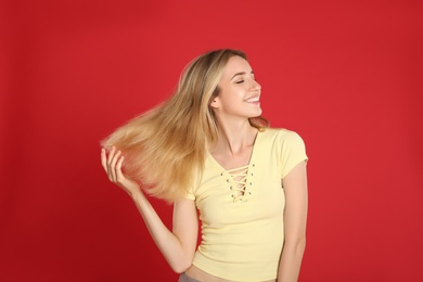 Photo of Portrait of beautiful young woman with blonde hair on red background