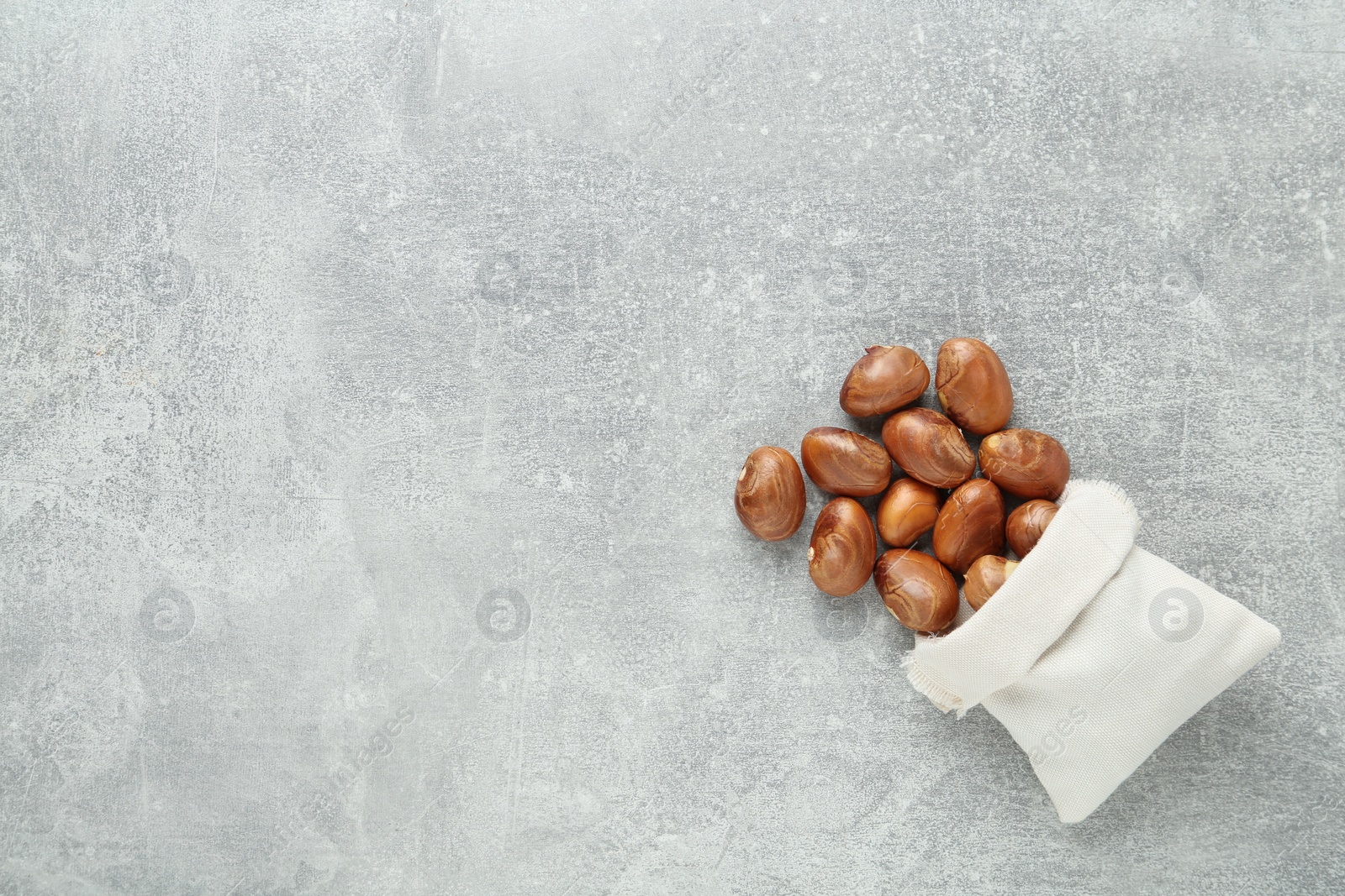 Photo of Overturned sackcloth bag with jackfruit seeds on light grey table, flat lay. Space for text