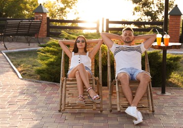 Image of Couple resting together in deck chairs outdoors