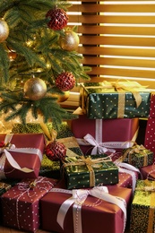 Photo of Pile of gift boxes near decorated Christmas tree indoors