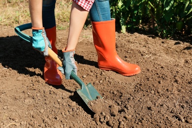 Photo of Woman digging soil with shovel outdoors. Gardening tool