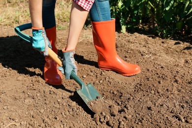 Woman digging soil with shovel outdoors. Gardening tool