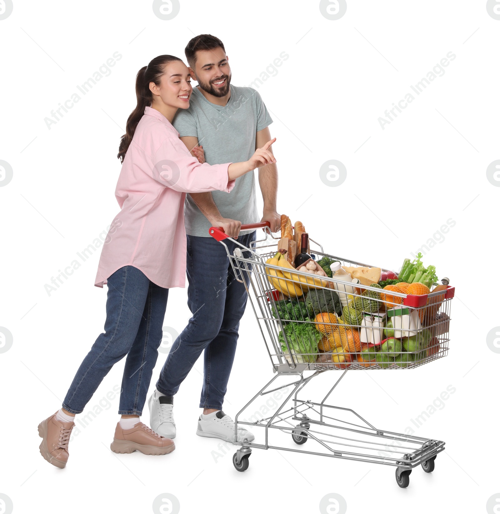 Photo of Happy couple with shopping cart full of groceries on white background