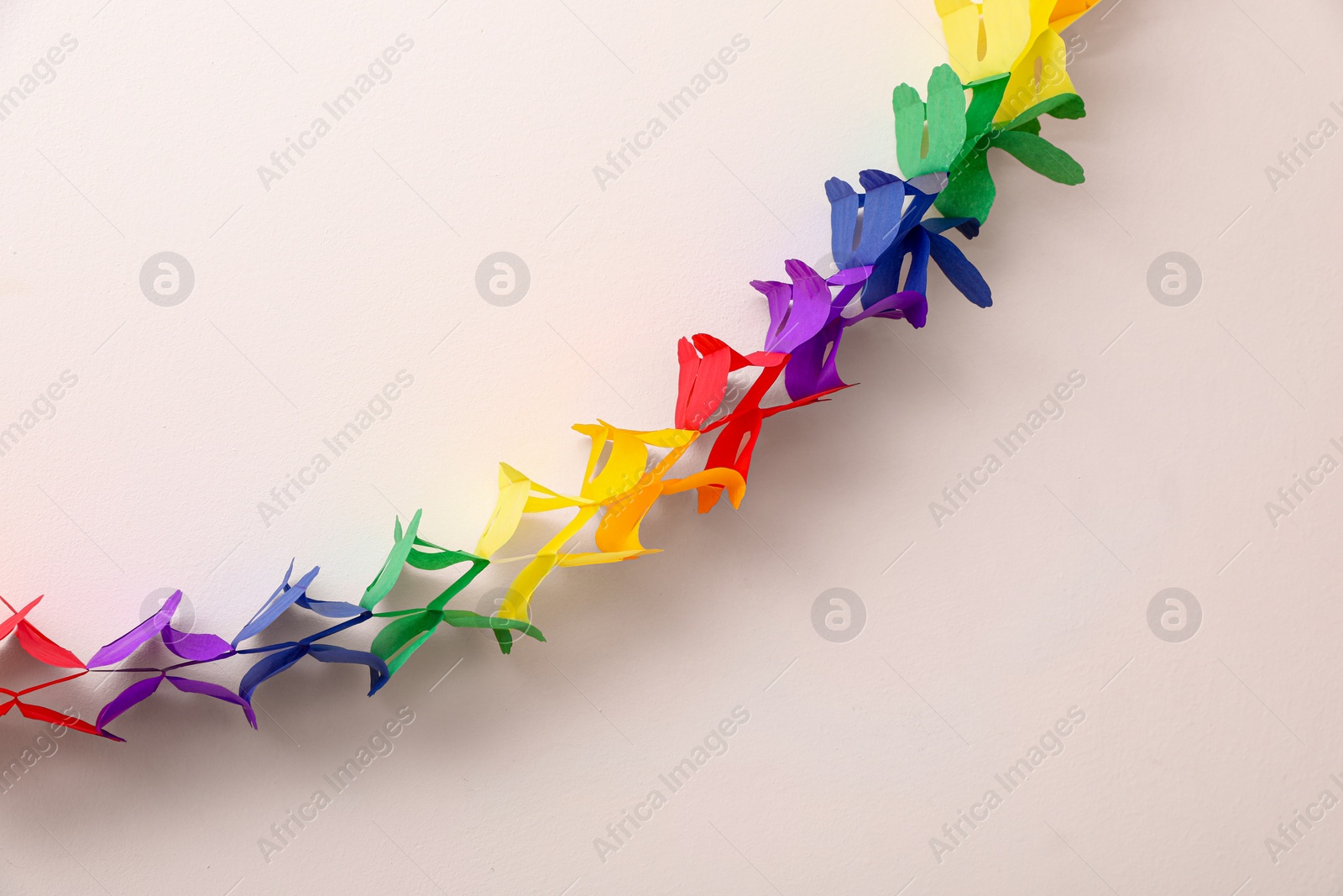 Photo of Rainbow paper garland on beige background. LGBT pride