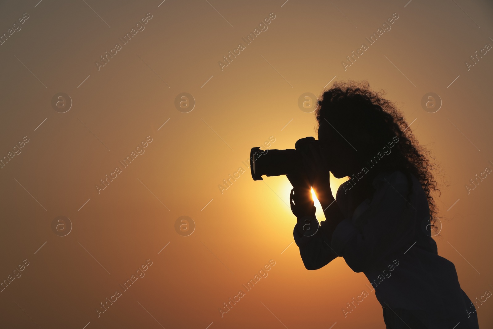 Photo of Photographer taking photo with professional camera outdoors at sunset