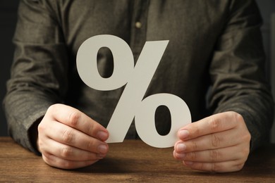 Photo of Man holding percent sign at wooden table, closeup