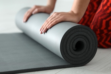 Young woman rolling yoga mat, closeup of hands