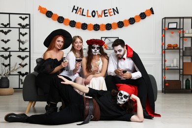 Group of people in scary costumes with cocktails celebrating Halloween indoors