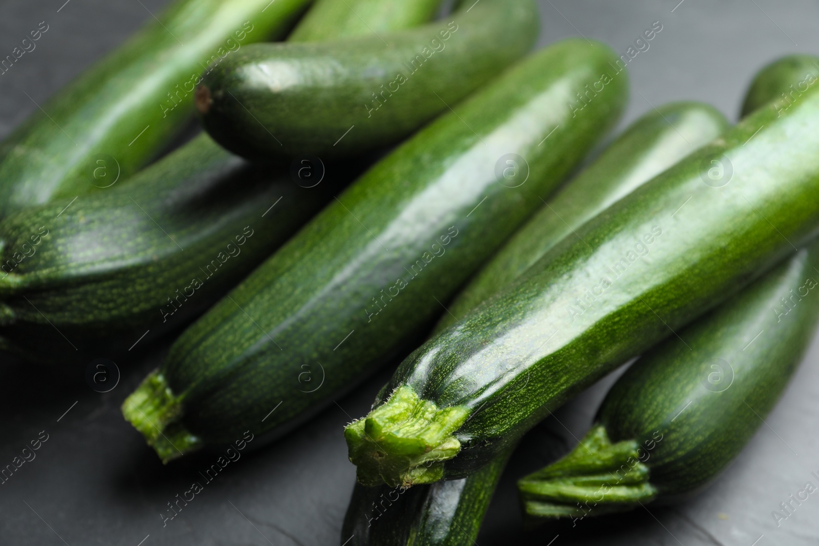 Photo of Green ripe zucchinis on black slate table, closeup