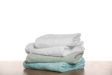 Photo of Soft colorful terry towels on wooden table against white background