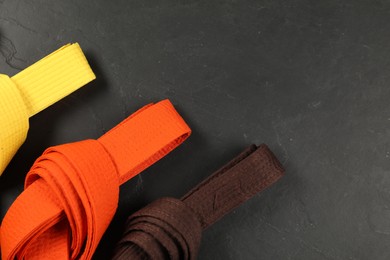 Photo of Colorful karate belts on gray background, flat lay. Space for text