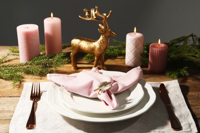 Photo of Stylish table setting with pink fabric napkin, beautiful decorative ring and festive decor on wooden background