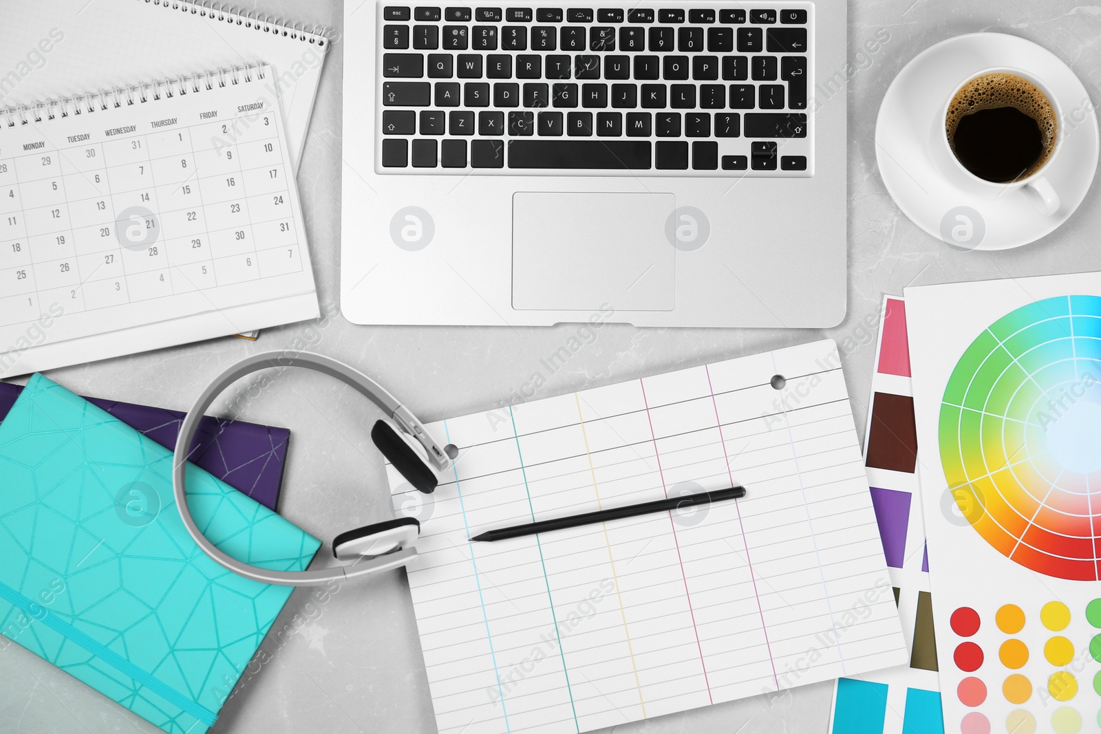 Photo of Flat lay composition with notebook, laptop and color palettes on light grey marble table. Designer's workplace