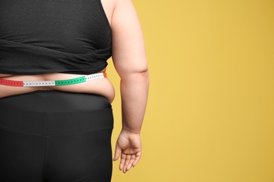 Photo of Overweight woman with measuring tape on color background