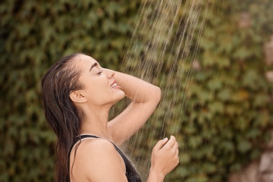 Photo of Woman washing hair in outdoor shower on summer day