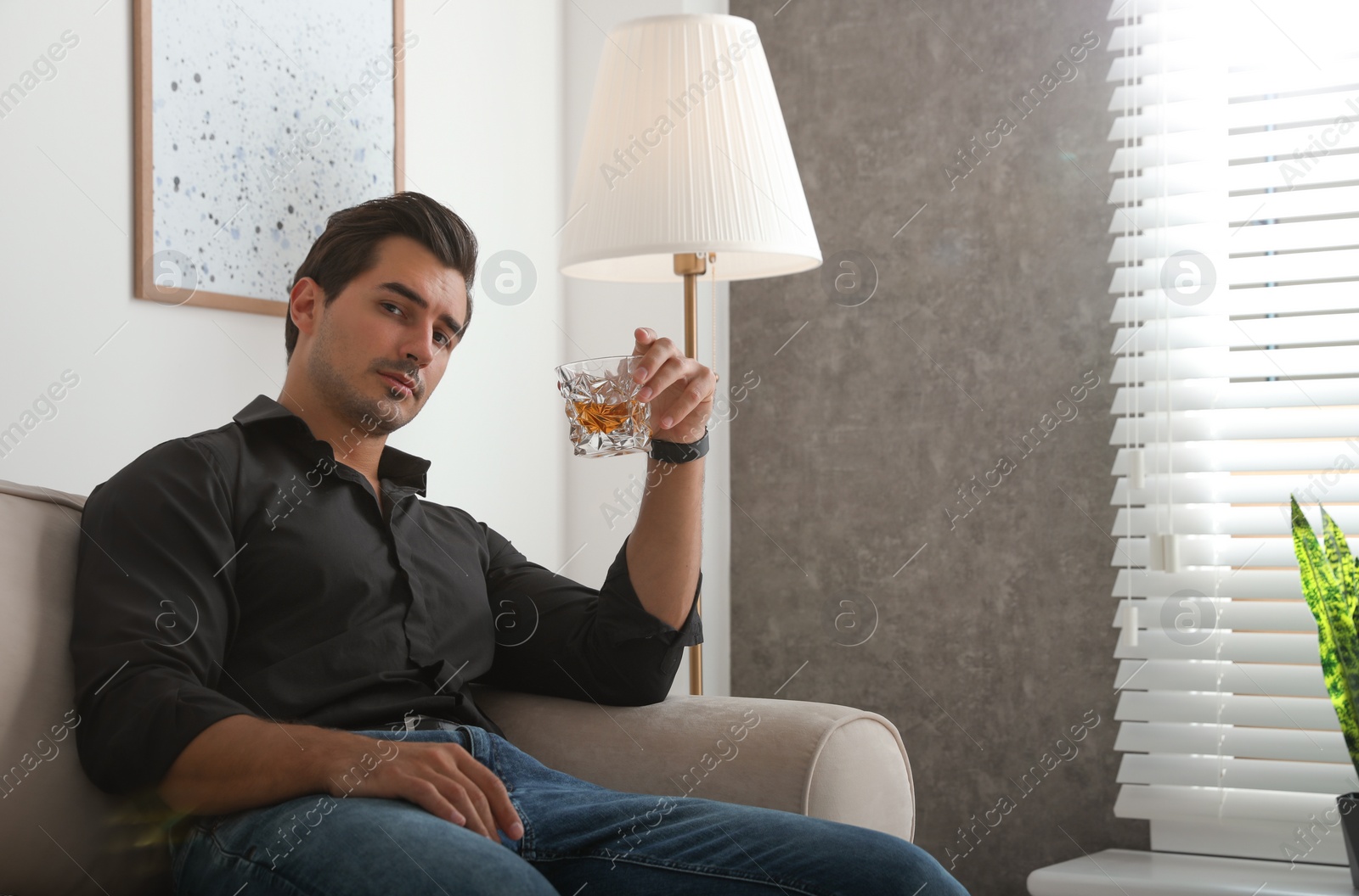 Photo of Young man with glass of whiskey at home