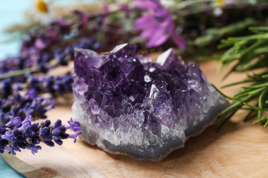 Photo of Amethyst and healing herbs on wooden board, closeup